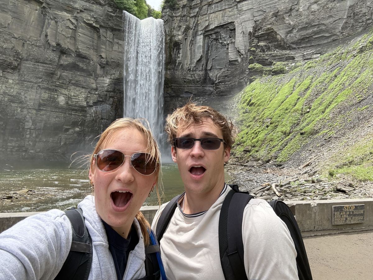 Natalie and me grinning in front of a tall waterfall